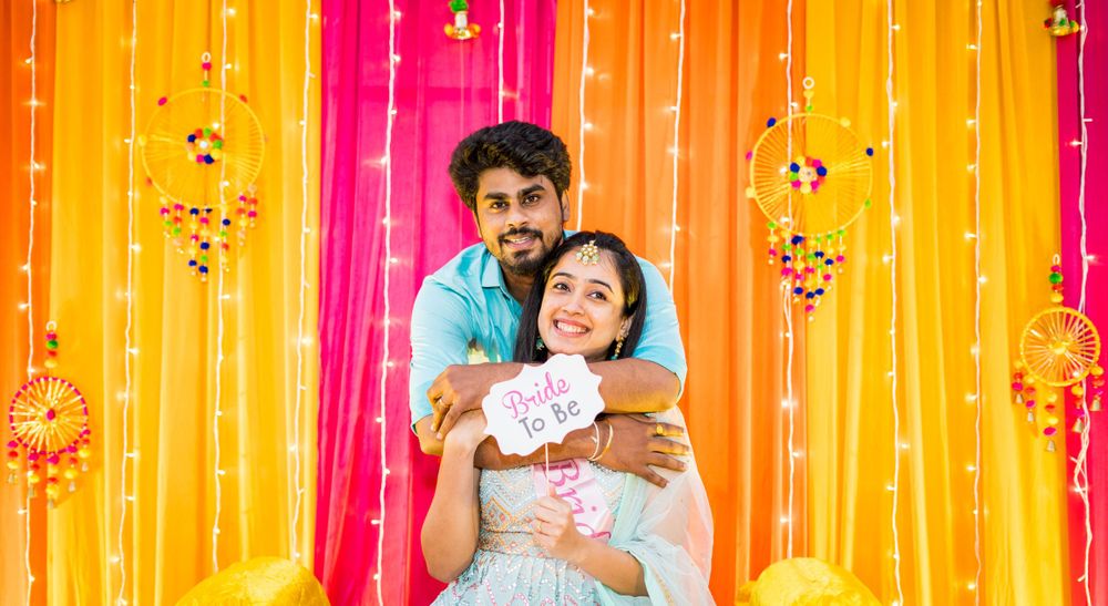 Celebration against vibrant yellow and pink draped backdrop with string lights.