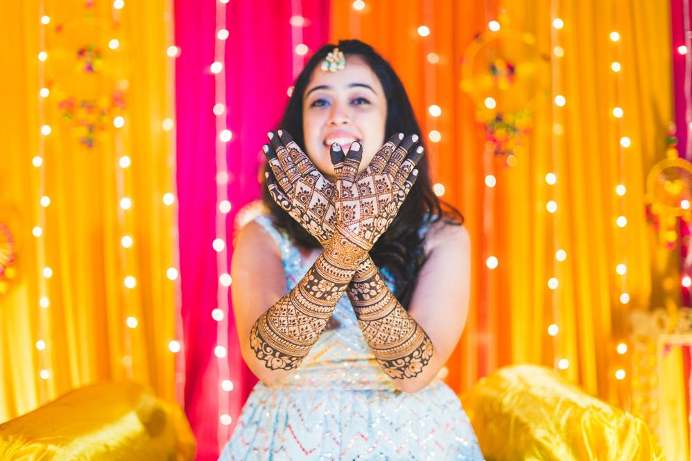 Playful pose showing off intricate henna designs during traditional Indian pre-wedding celebration.