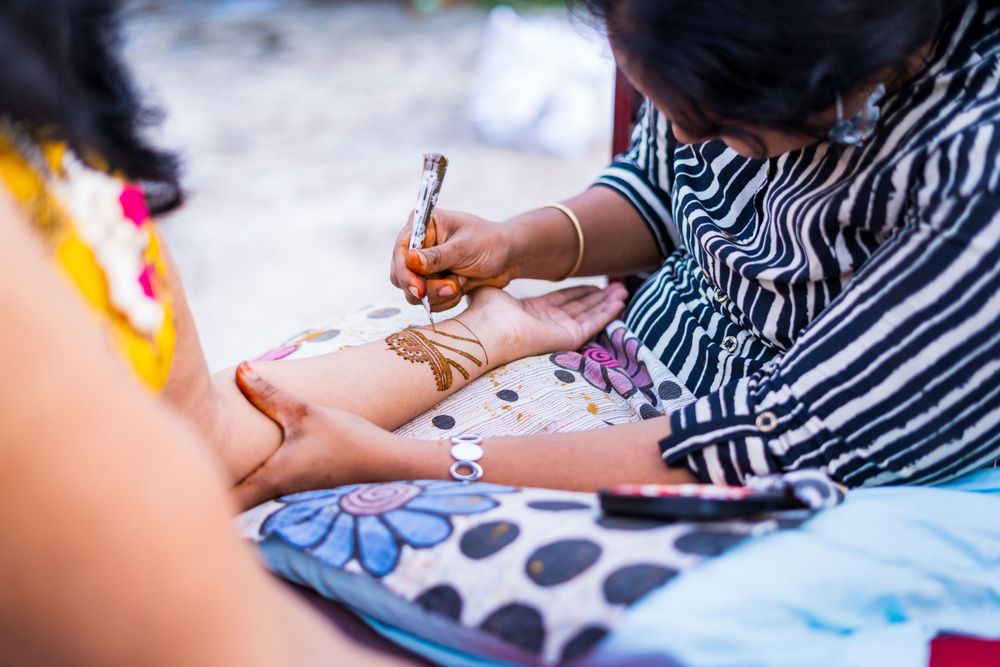 Close-up shot of hands applying henna mehndi designs at a traditional celebration.