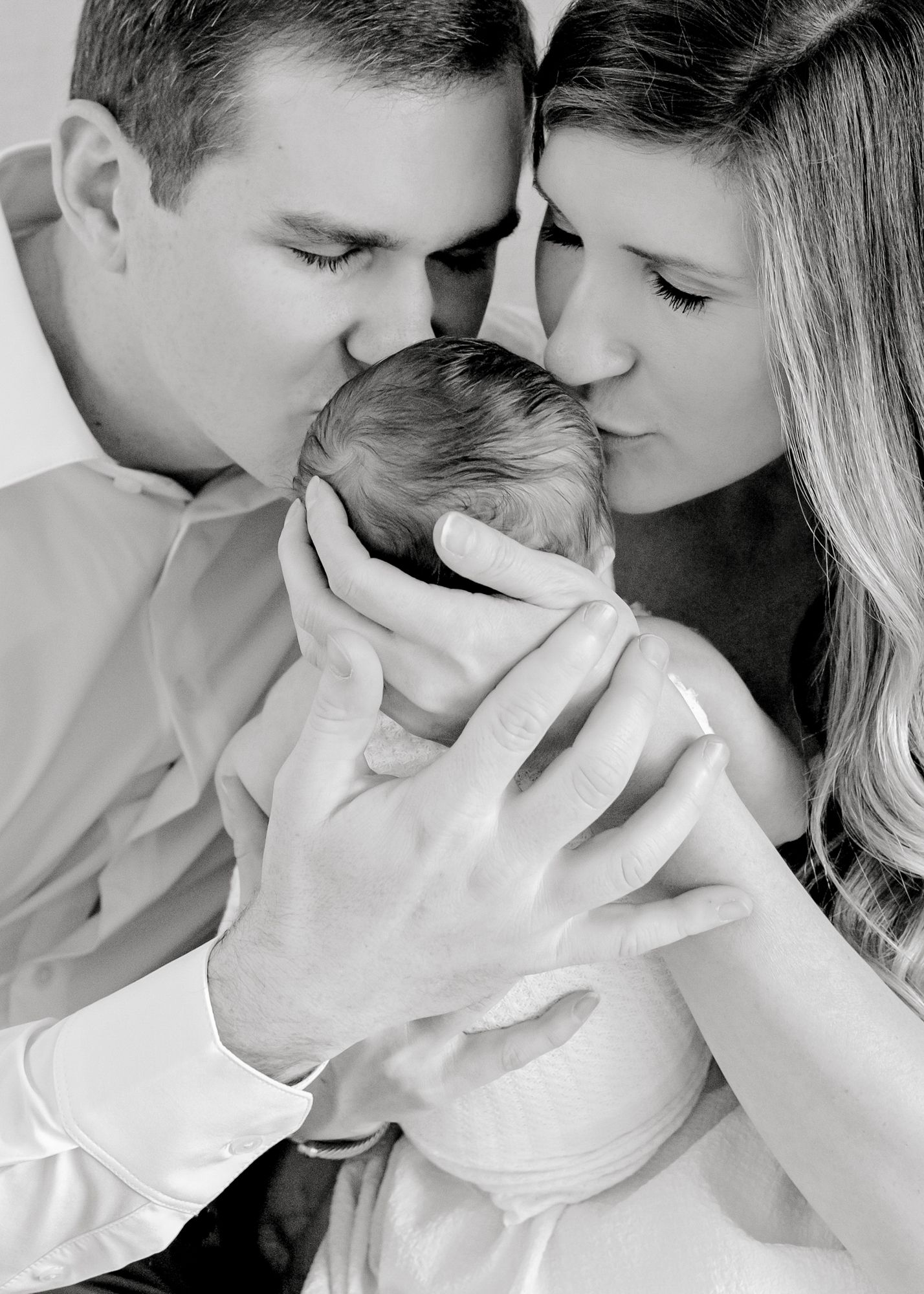 Black and white intimate portrait of parents with newborn.