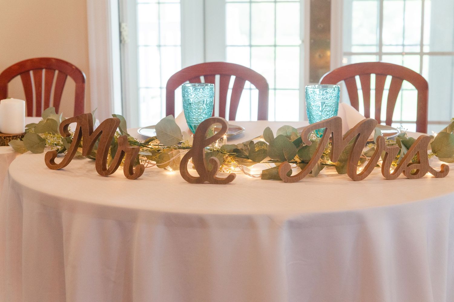 Banquet tables decorated with turquoise glassware and white linens in a bright reception hall.