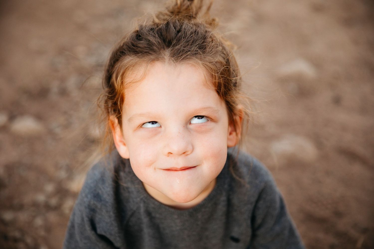 A close-up portrait of a child with a playful expression outdoors.