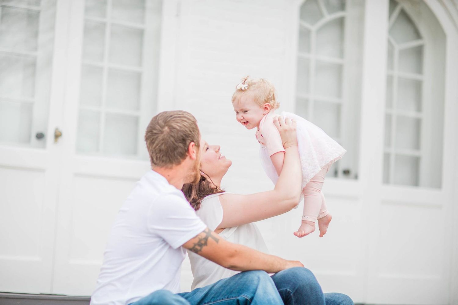 A tender parenting moment captured in soft lighting against a white architectural background.