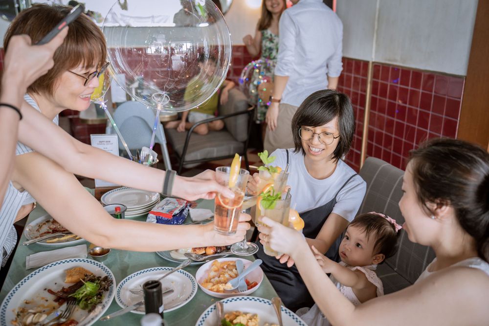 A group toasting drinks around a table with food during a celebration.