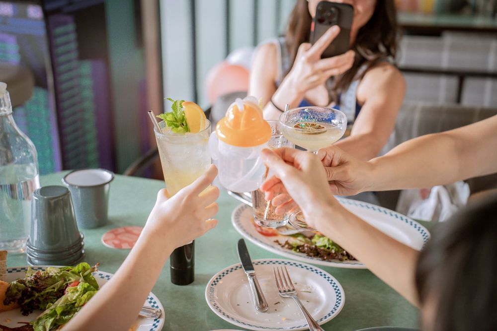 Overhead view of people sharing food and drinks at casual restaurant gathering.