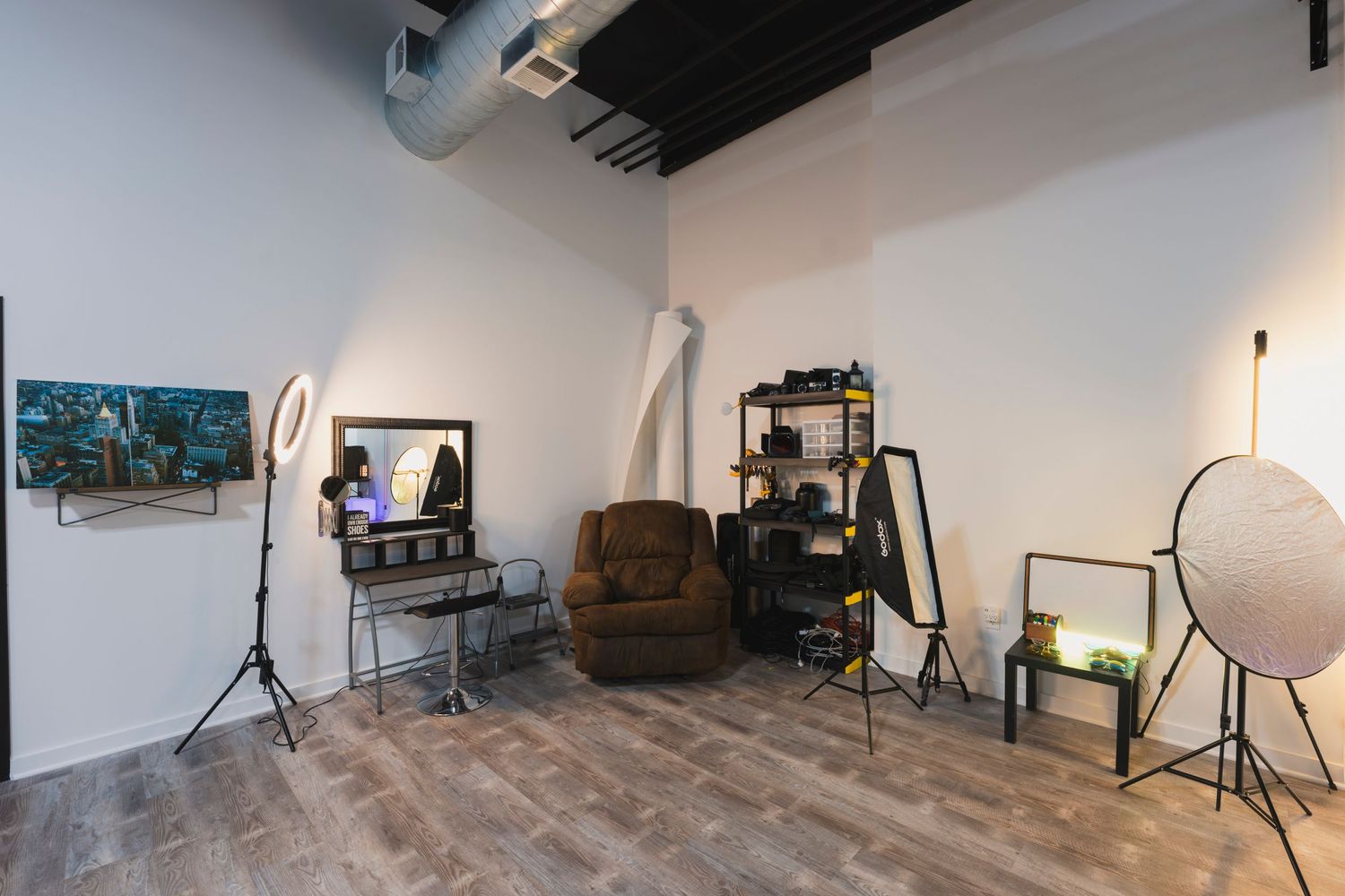 Photography studio corner with vintage chair, lighting equipment and professional gear setup.