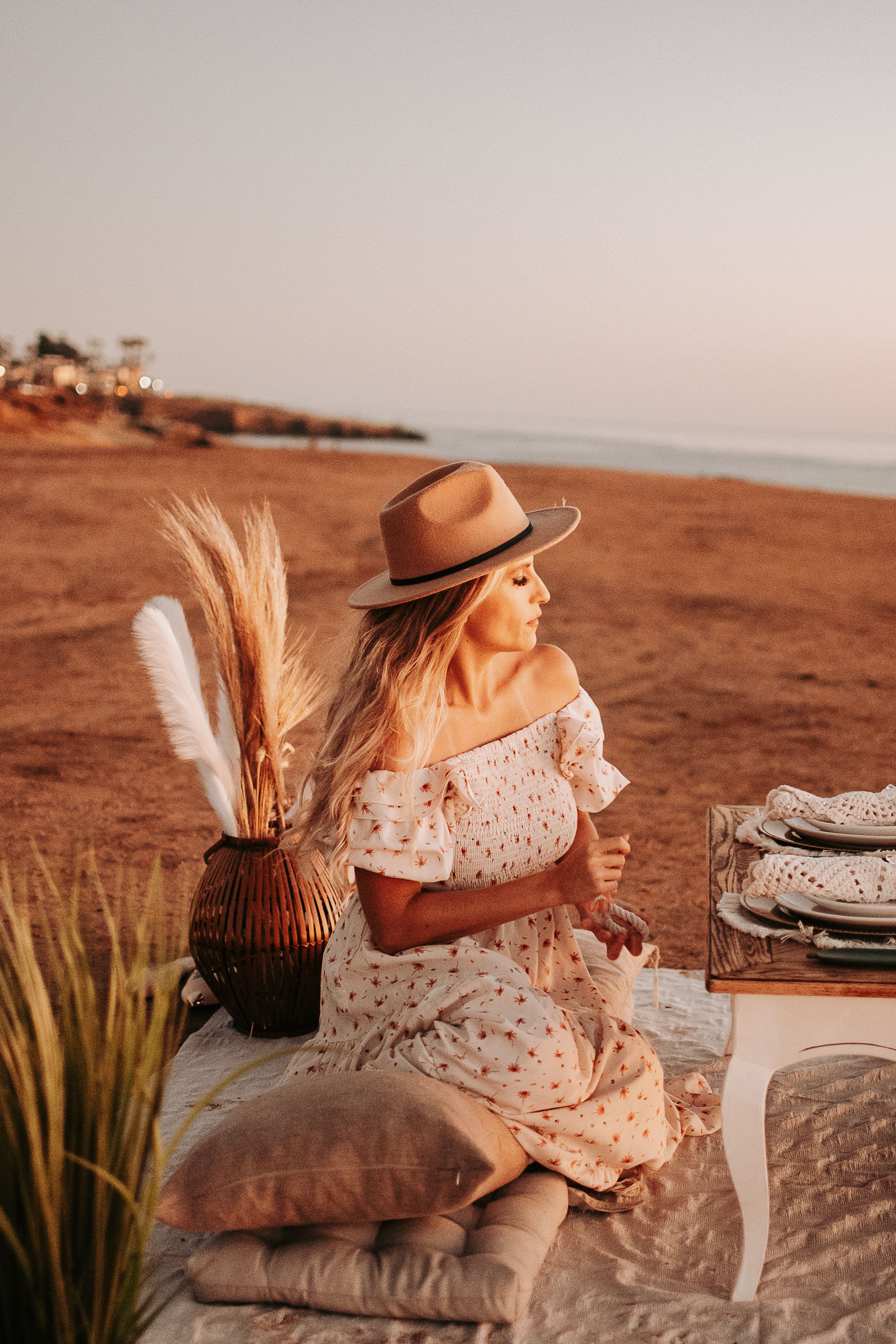 Beachside picnic setup with vintage decor and table settings during golden hour.
