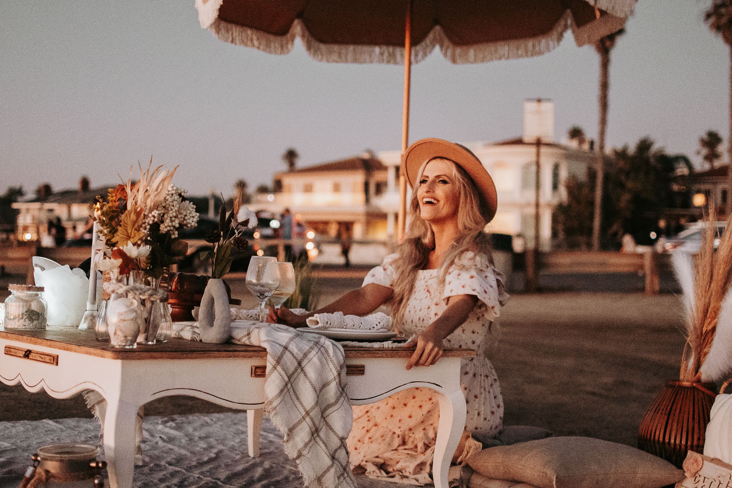Outdoor beach dining setup with vintage decor and table settings at sunset.
