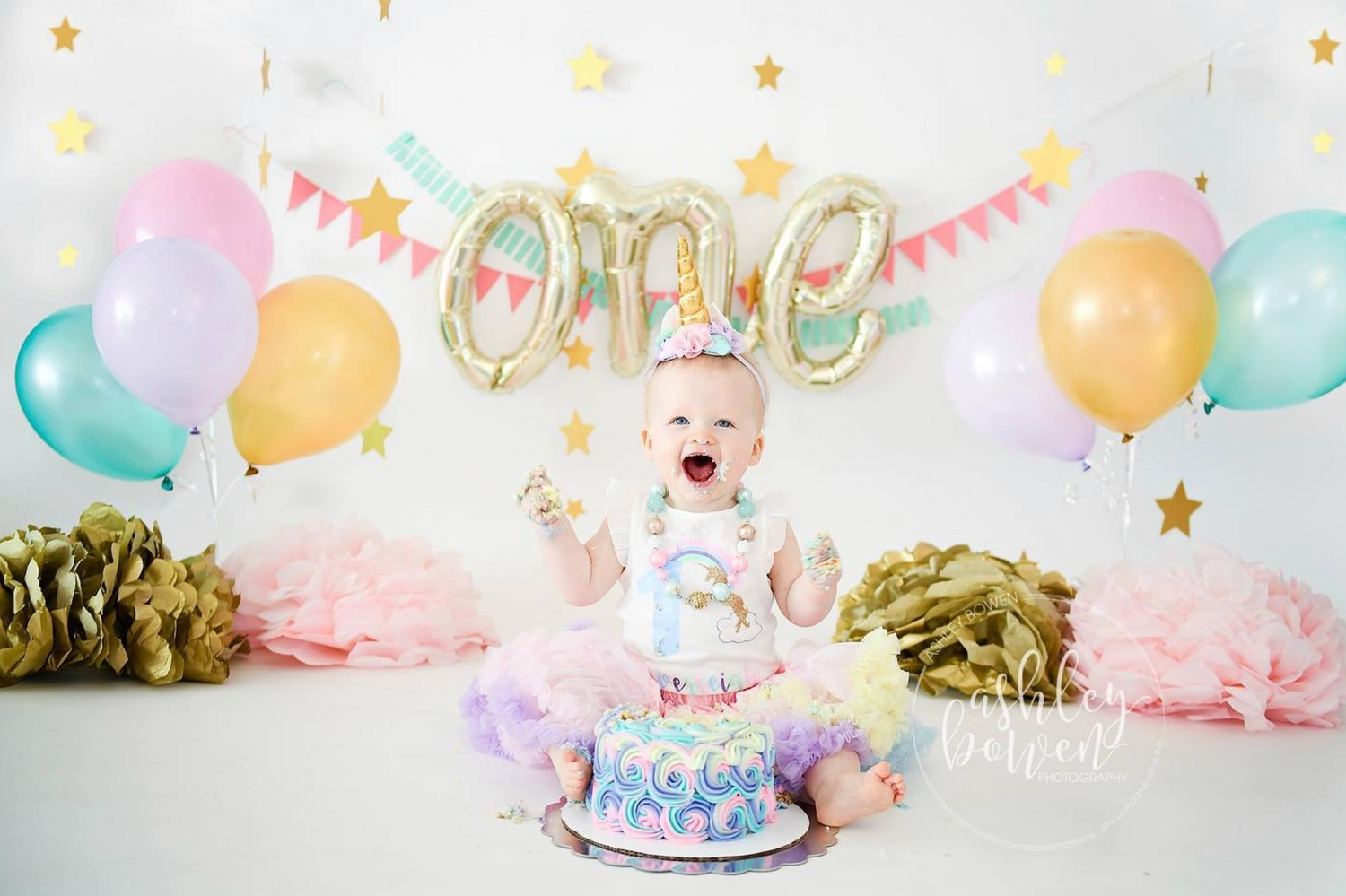 Baby's first birthday cake smash with unicorn theme, colorful balloons and decorations.