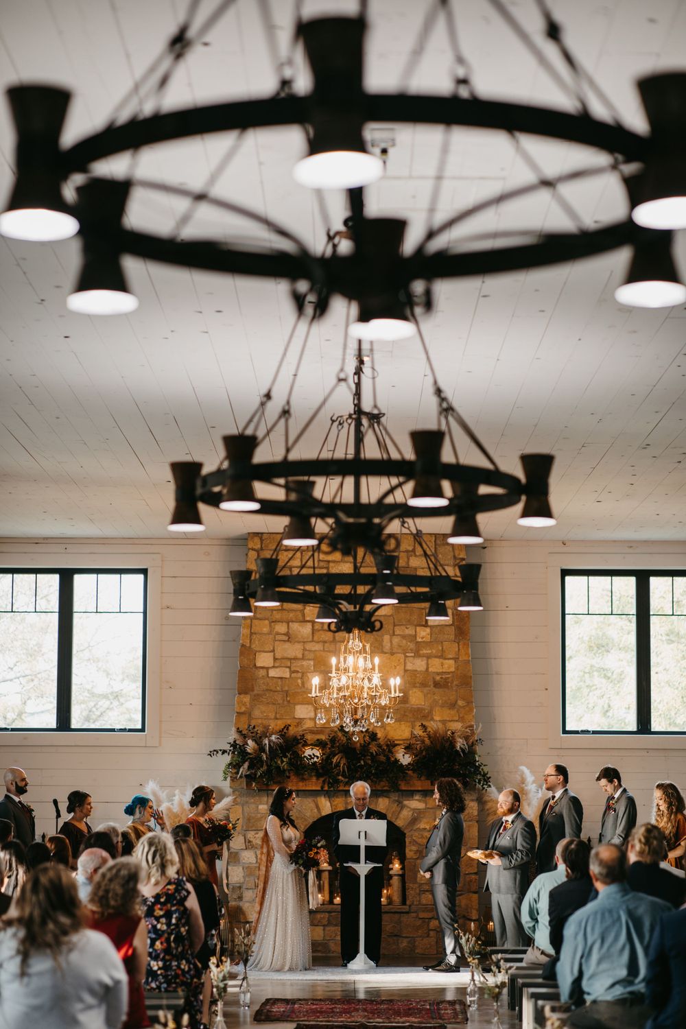 Overhead view of elegant barn wedding ceremony with stone fireplace and ornate chandelier.