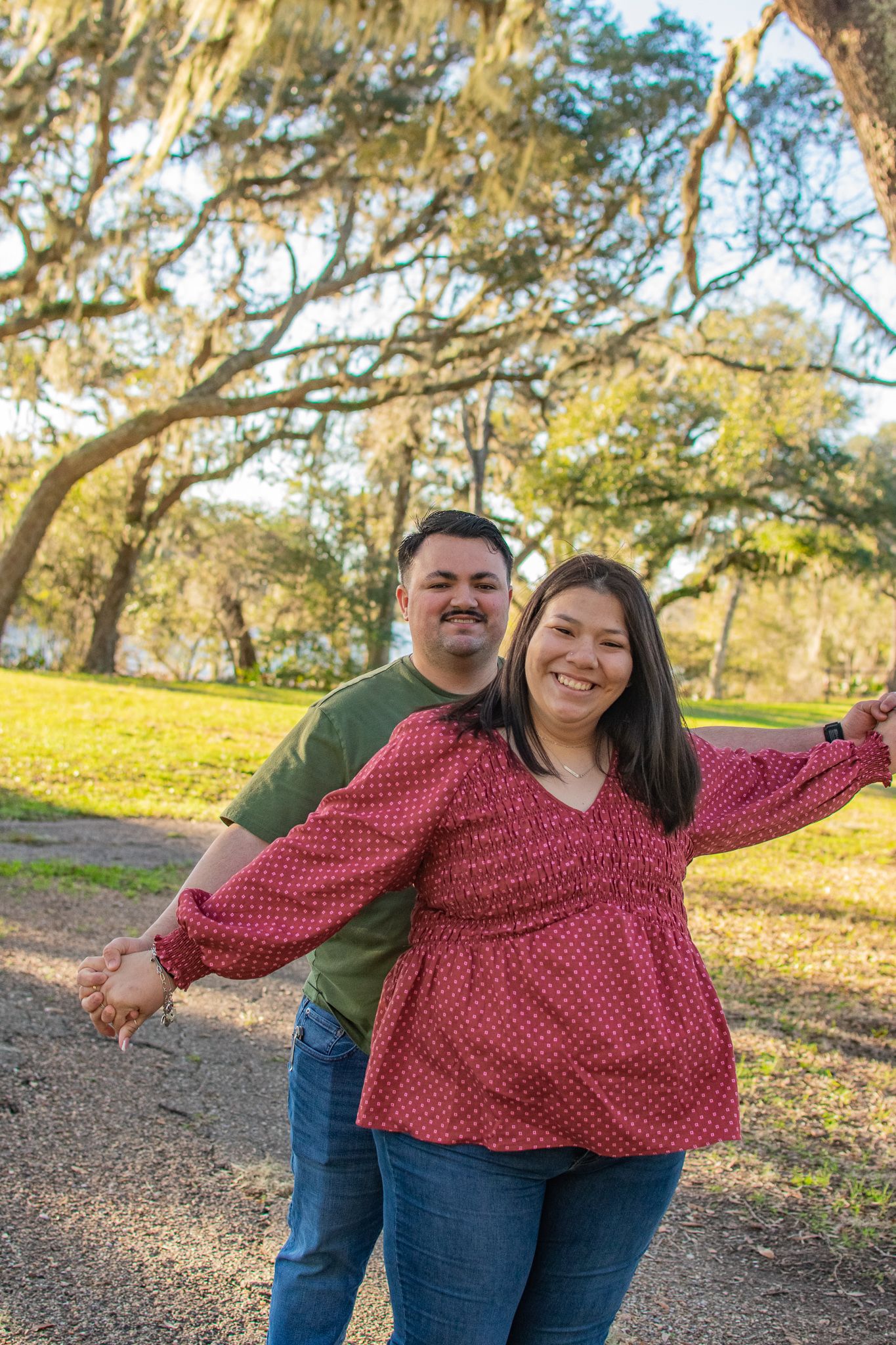 Joyful couple having fun on a path beneath spanish moss draped trees.