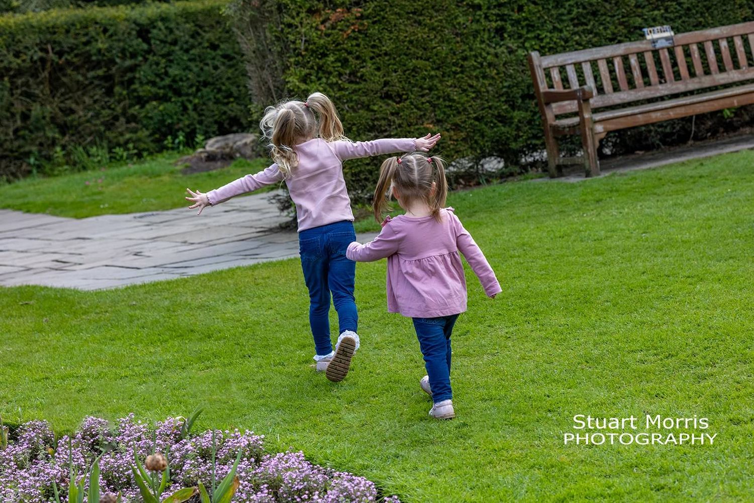 2 little girls run through the park arms out like an airplane. mini outdoor portrait session at Walton hall.