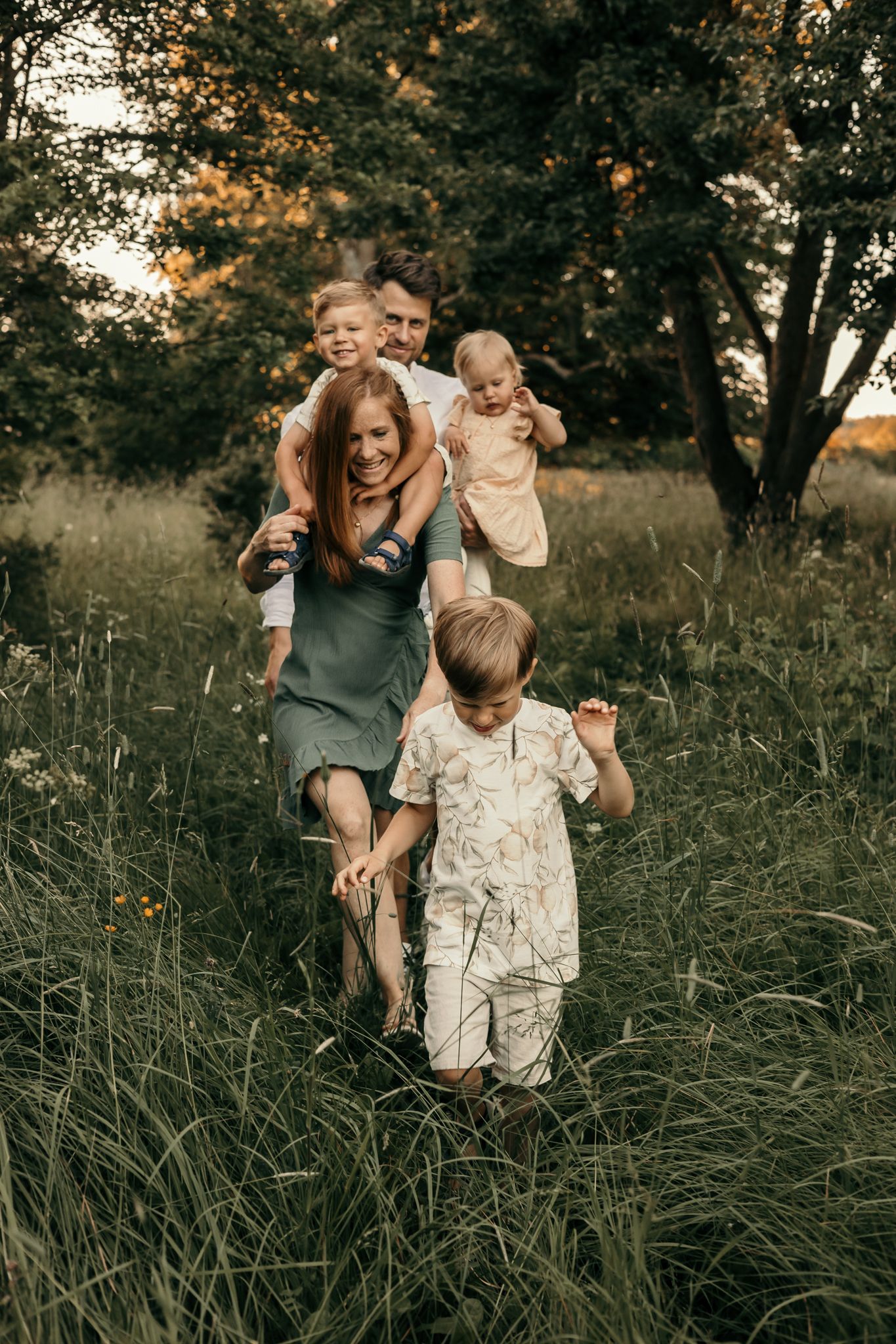 Lekfull sommarfotografering i det gröna av familj med tre barn.