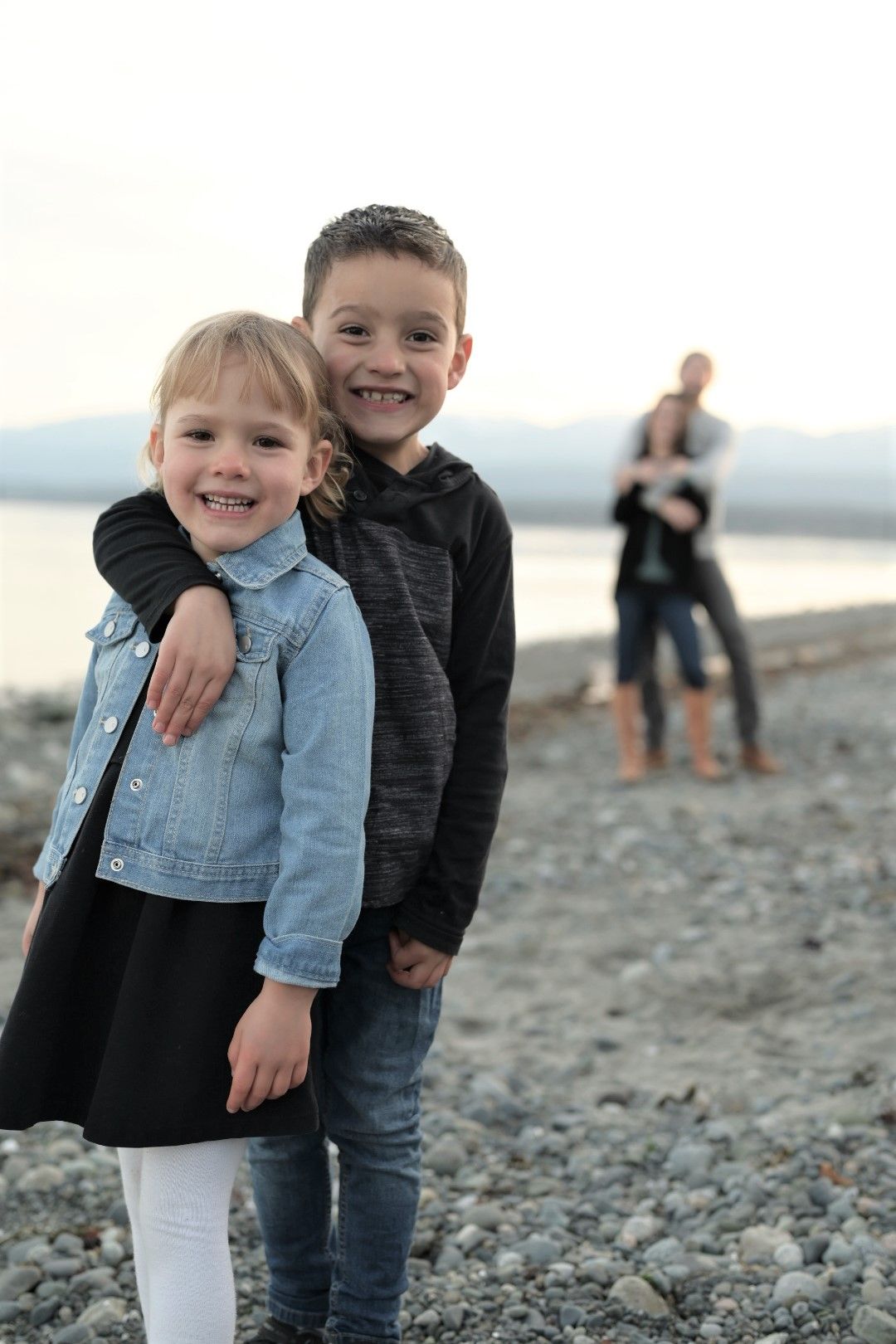 Photo of brother in and sister in foreground and mom and dad in the background.