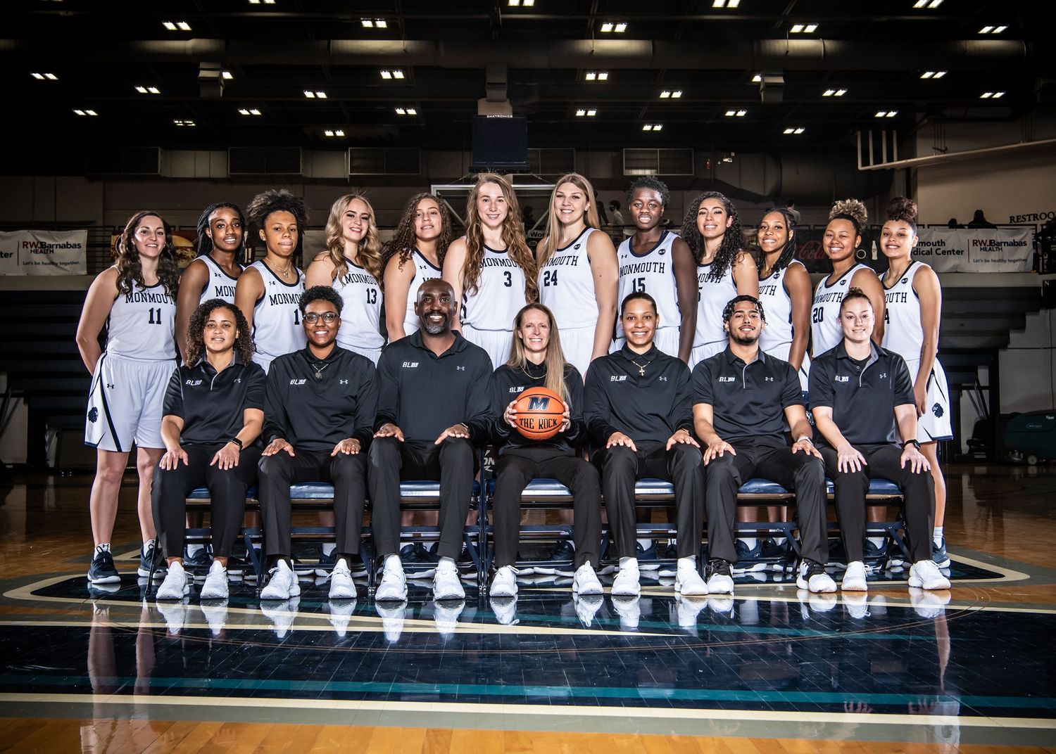Basketball team photo showing players and coaches lined up in matching uniforms.