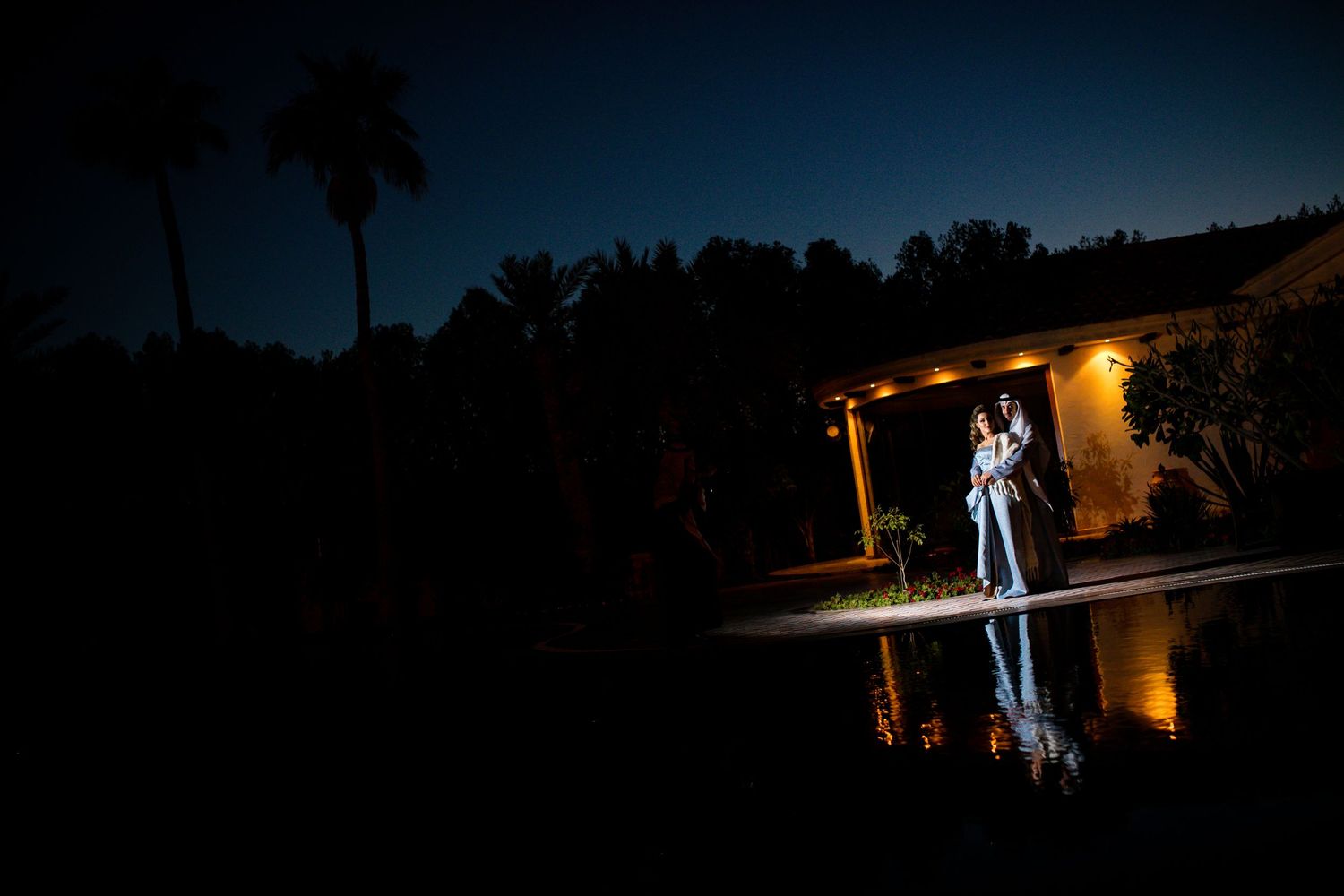Dramatic nighttime wedding portrait with reflection in dark water.