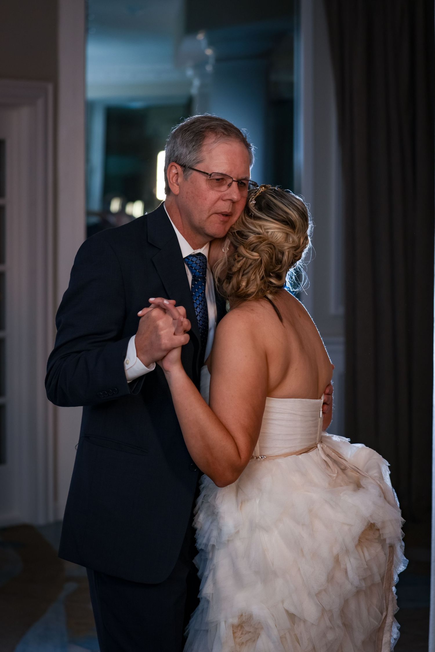 A tender moment during a father-daughter dance at an evening wedding reception.