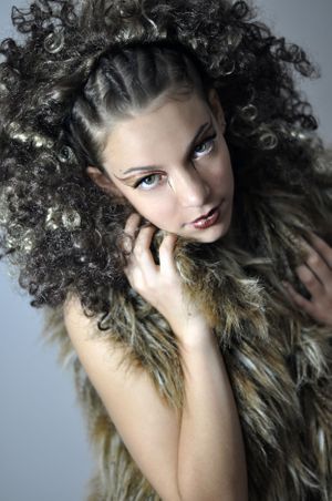 Dramatic fashion portrait with wild curly hair and feathered costume.