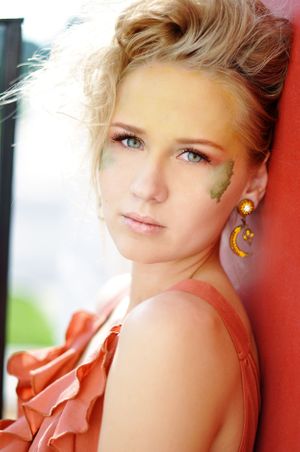 Summer fashion portrait with coral top and decorative leaf detail.