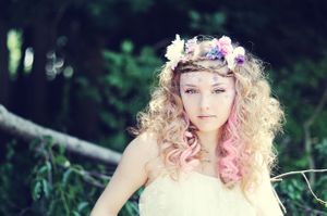 Ethereal fairy-like portrait with floral crown and soft pastel curls in nature.