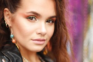 Close-up portrait with purple bokeh background and turquoise earring details.