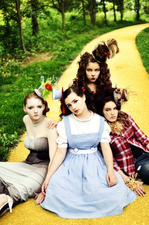 Wizard of Oz themed group photo on yellow brick road with costumes and whimsical props.