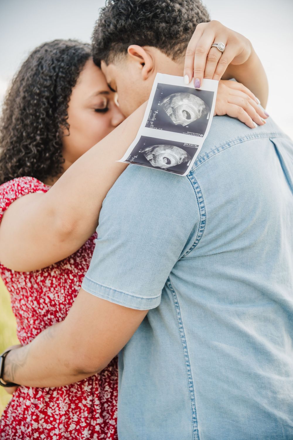A touching pregnancy announcement moment showing hands holding ultrasound photos while embracing.