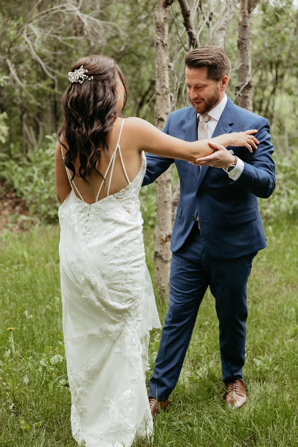 A couple shares a romantic dance moment in a sunlit wooded area during their wedding.