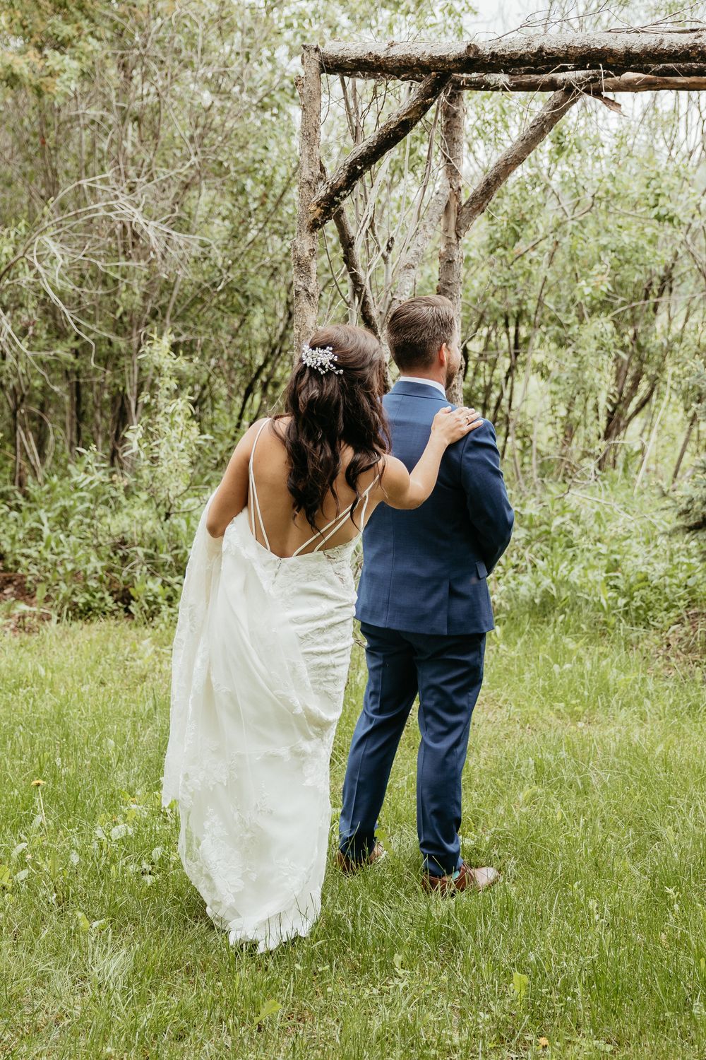 Couple walking through lush garden setting in wedding attire.