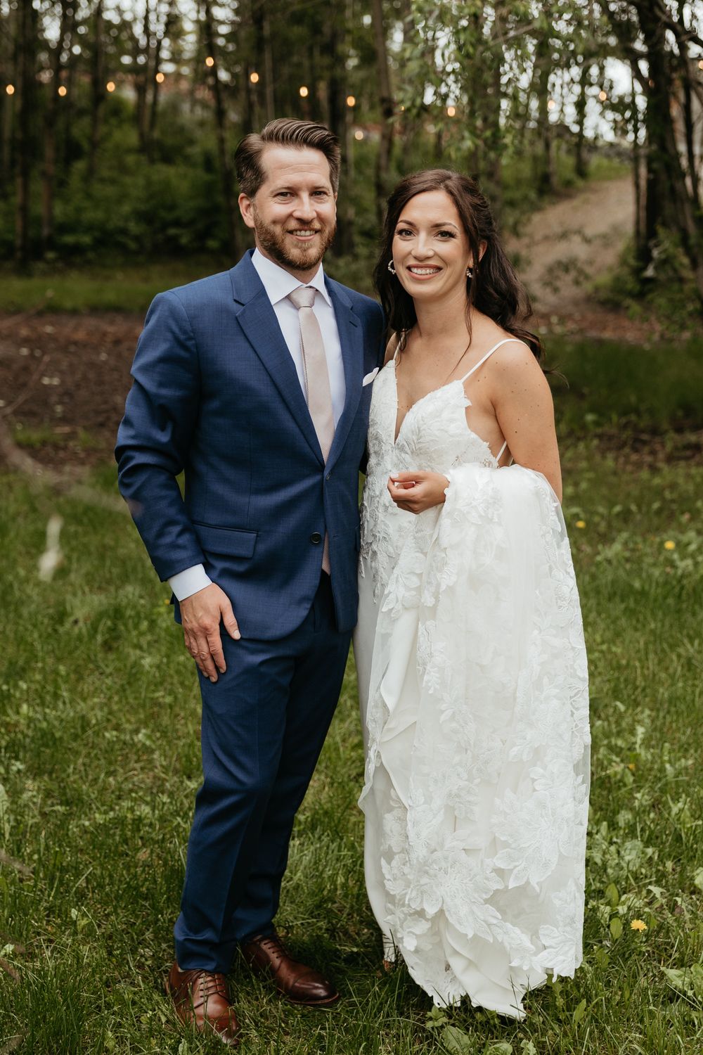 A couple in wedding attire shares joyful moments in a natural outdoor setting.