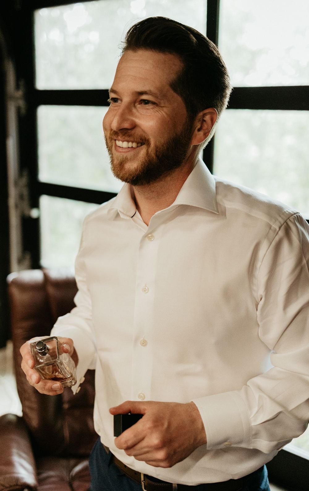 Person in white dress shirt holding a drink at social gathering.