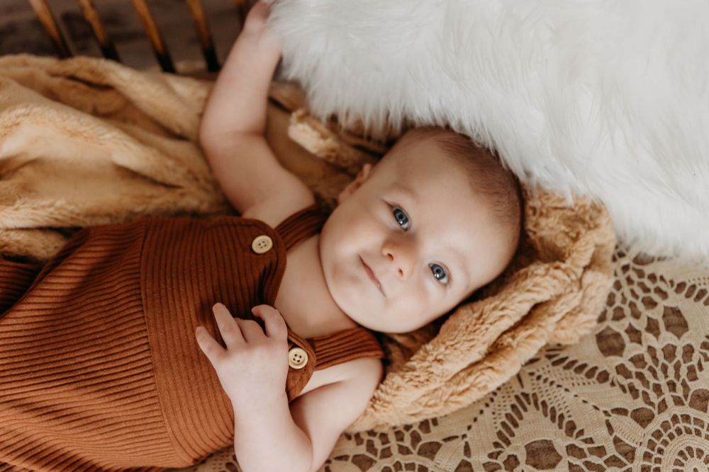 Baby lying on soft textured blanket in warm lighting.