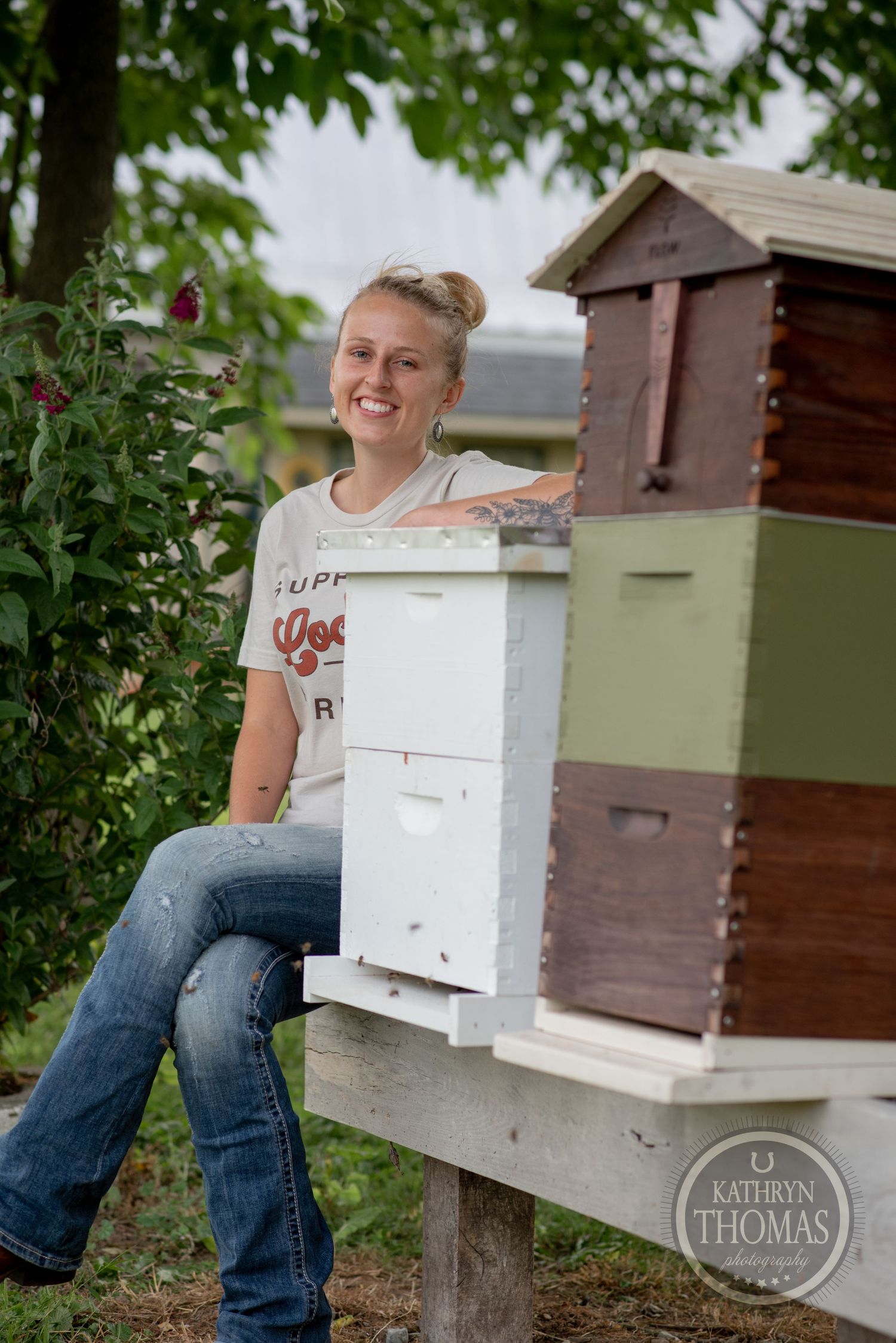 White and brown beehive boxes arranged in a garden setting with flowering plants.
