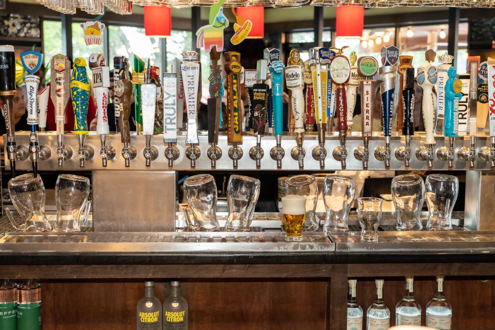 Bar counter with extensive row of beer taps and glassware displayed.