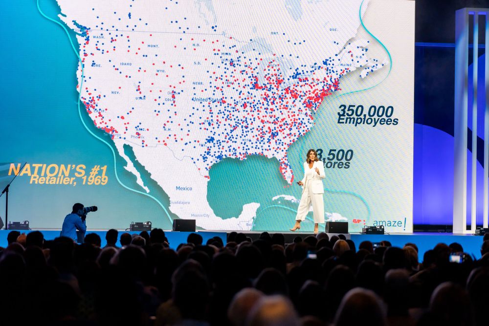 Large map of the United States displayed on stage showing data points with red and blue dots during a presentation.