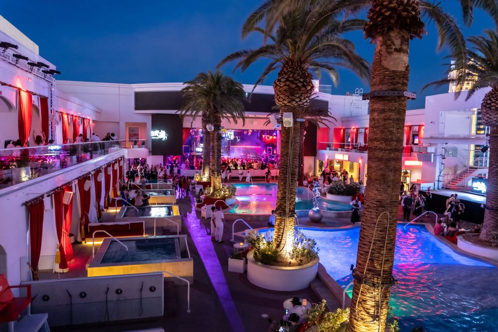Luxury resort courtyard with illuminated pool and palm trees at night.