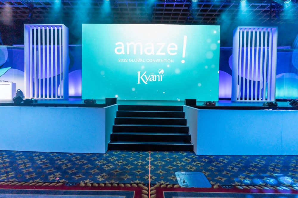 Blue-lit stage setup with Amaze branding and steps at corporate event.