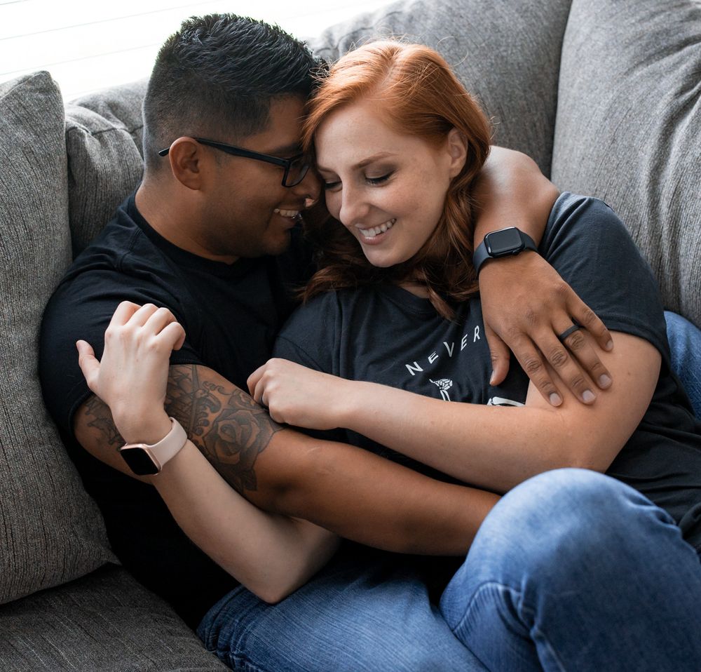 Intimate couple sharing tender moments while relaxing on grey sofa.