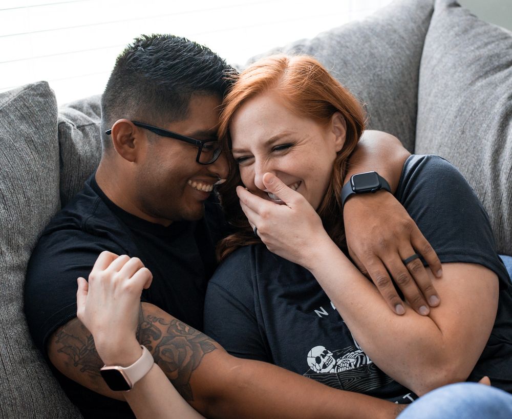 Intimate couple sharing tender moments together on a couch in casual attire.