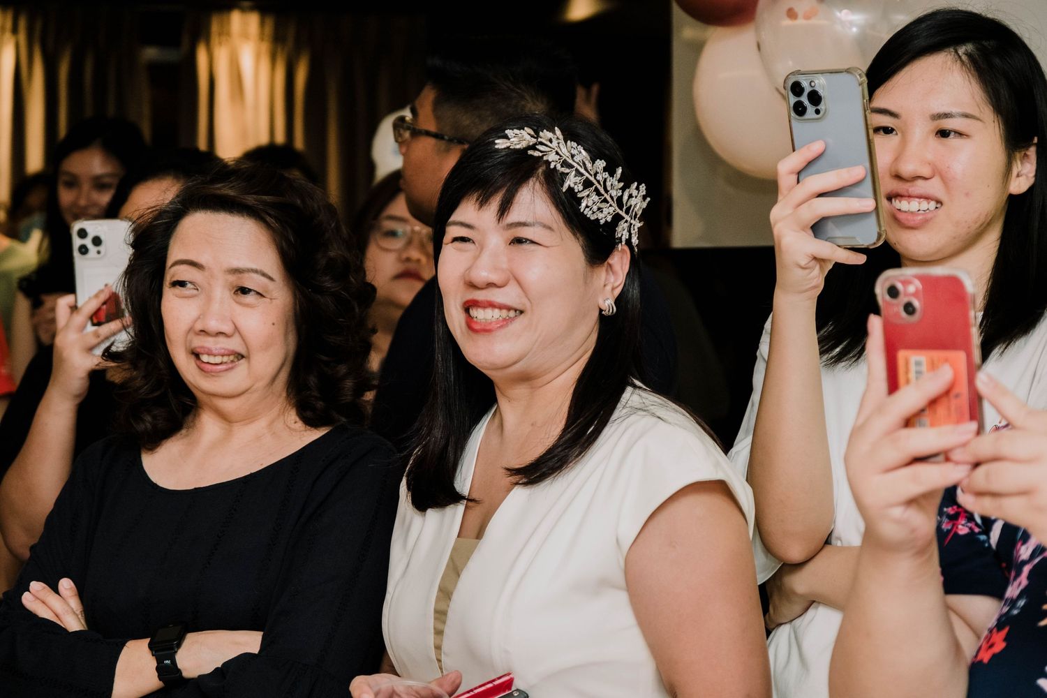 Party guests holding phones to capture moments at a celebration event.