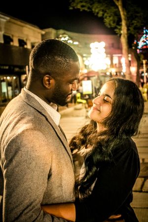 Intimate nighttime portrait of couple sharing tender moment on city street.