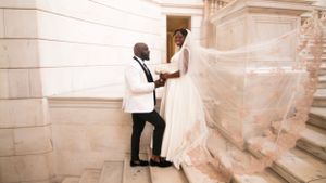 Wedding couple posing on grand staircase with flowing veil.