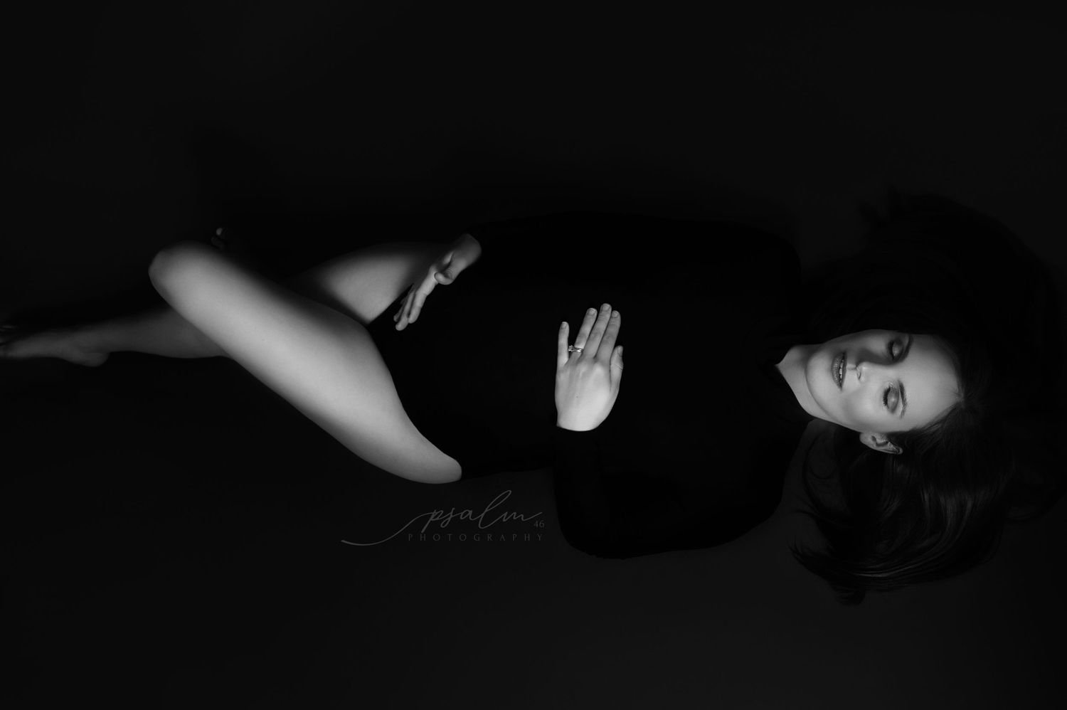 Dark and moody black and white maternity photography series with dramatic shadows.