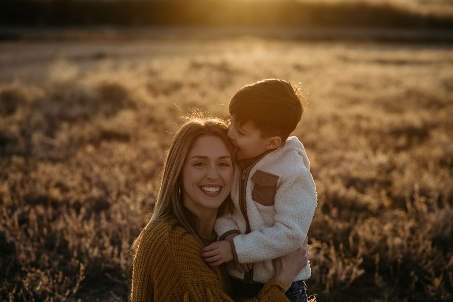 a son licks his moms head after she asks him to kiss her while she laughs