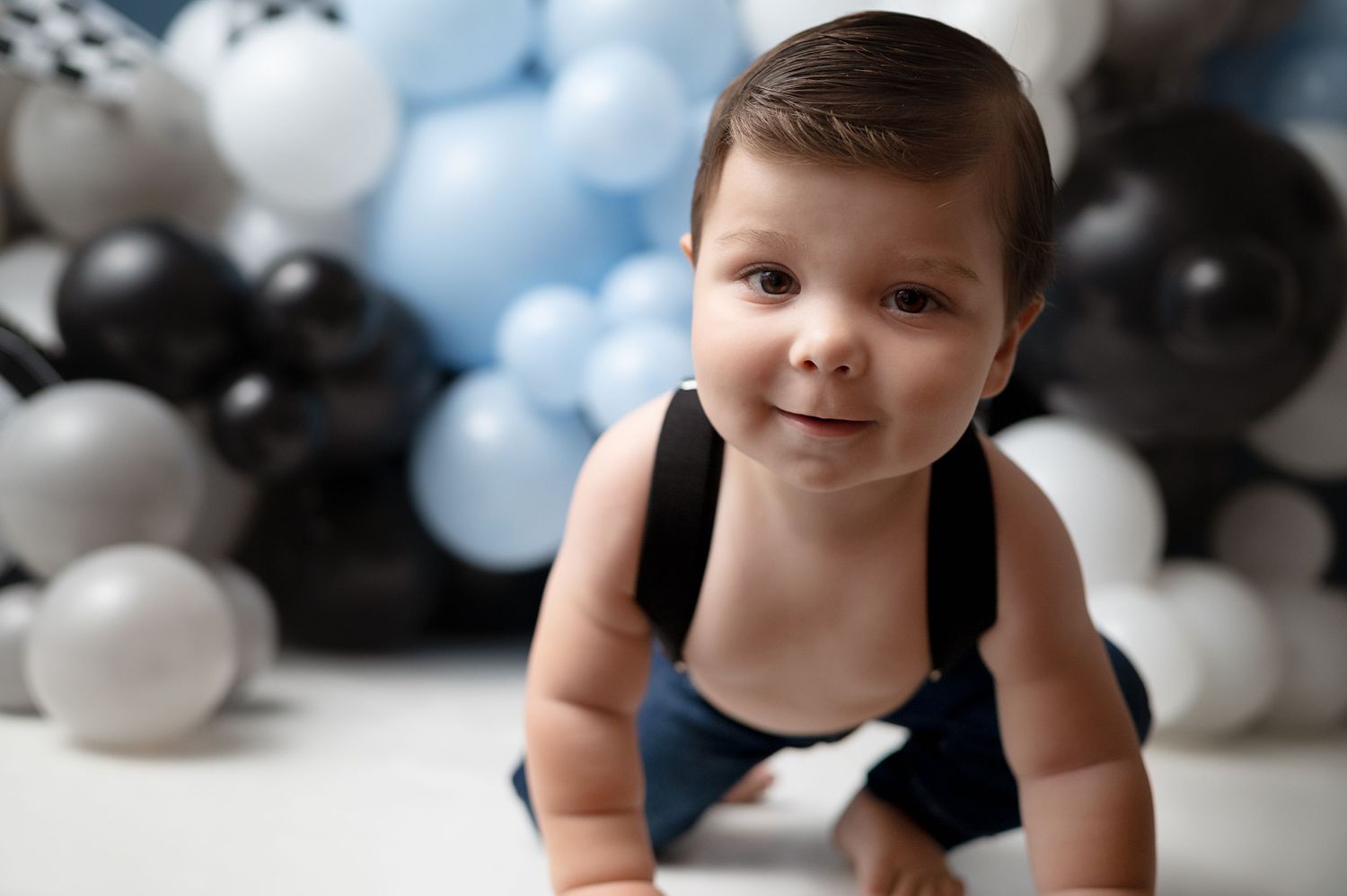 Close-up portrait against decorative balloon backdrop with checkered pattern.