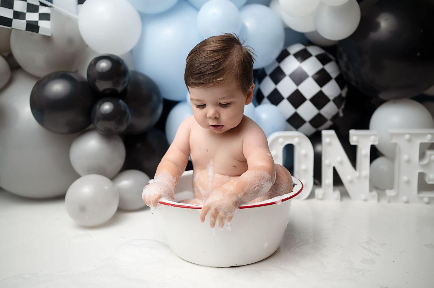 Racing-themed first birthday setup with checkered patterns and balloon garland.