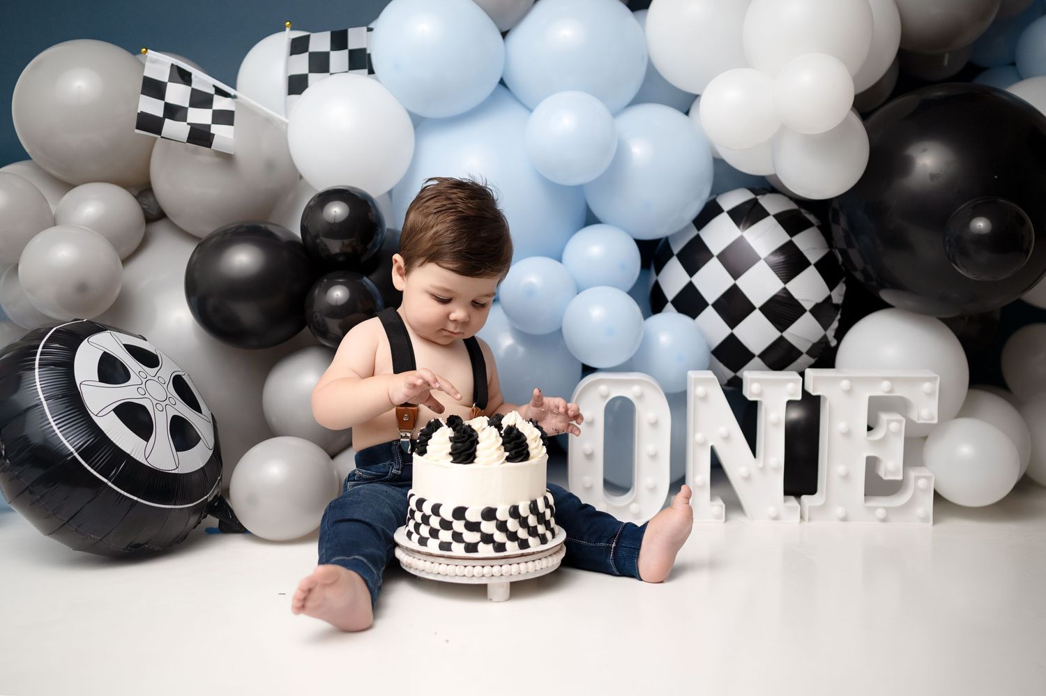 First birthday photo session with racing theme and dramatic balloon arrangements.