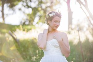 A bride in a strapless gown smiles in golden afternoon light.
