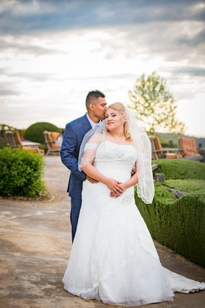 A romantic sunset wedding portrait showing a couple in elegant attire on a garden terrace.