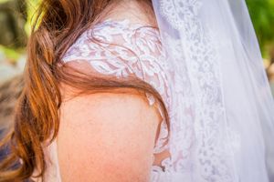 Close-up detail of delicate white lace on a wedding dress with floral embroidery.